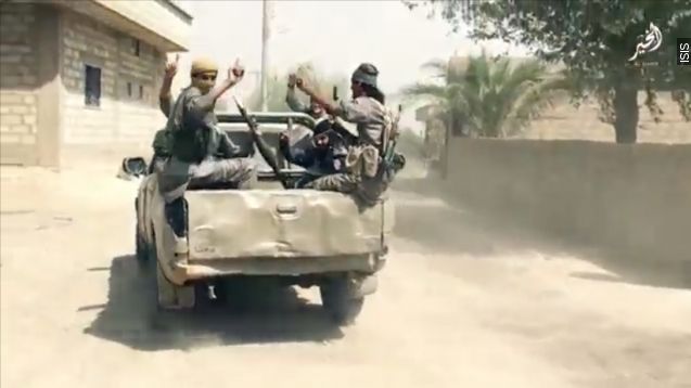 Members of ISIS ride in the back of a truck.
