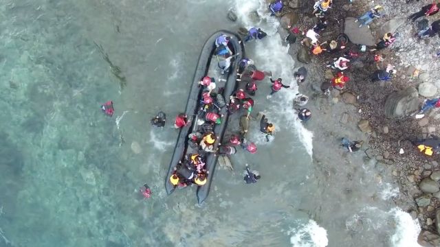 An aerial view of refugees arriving on a Greek shore.
