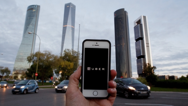 In this Photo Illustration a smart phone displays a picture with the logo of the news taxi app 'Uber' near the Cuatro Torres 'Four Towers' business area on October 14, 2014 in Madrid, Spain.
