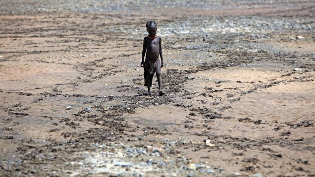 A boy from the remote Turkana tribe in Northern Kenya walks across a dryed up river at Kokuro