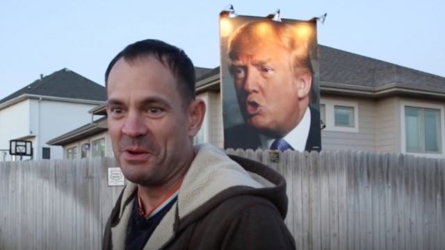 A man stands by his huge Trump sign