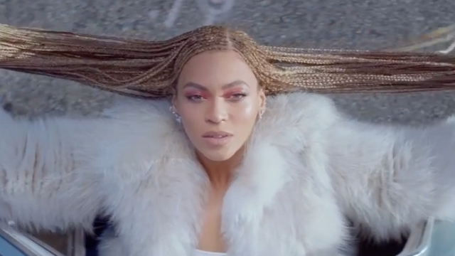 Beyoncé is pictured holding her hair out to either side of her head.