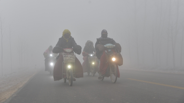 A group of cyclists travel through thick smog in China.