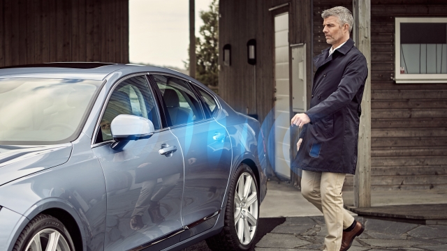 A man approaches his Volvo vehicle as his mobile phone triggers the car's unlock switch.