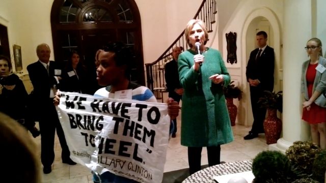 As the fight for the Democratic Black vote continues, Hillary Clinton was confronted Wednesday by a Black Lives Matter activist at a late-night fundraiser.The activist, Ashley Williams, from Charlotte, North Carolina, held up a sign that read "we have to bring them to heel," referring to a controversial statement Hillary made in 1996 about at-risk youth.
