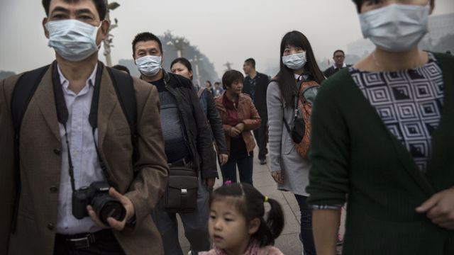 Chinese adults wear masks on a smoggy day near Tiananmen Square