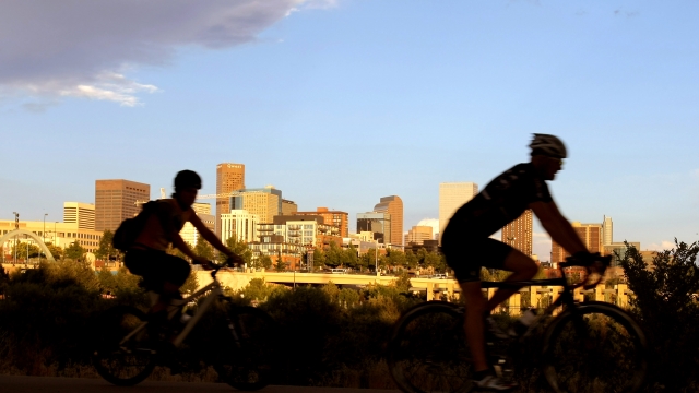 Cyclists pedal along the South Platte River across from the downtown city skyline on August 12, 2008 in Denver, Colorado.