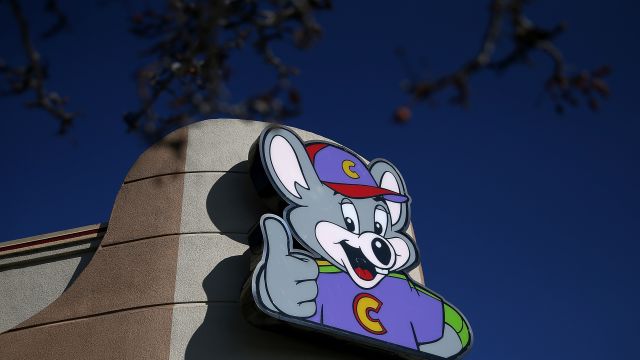 A sign is posted in front of a Chuck E. Cheese's restaurant.