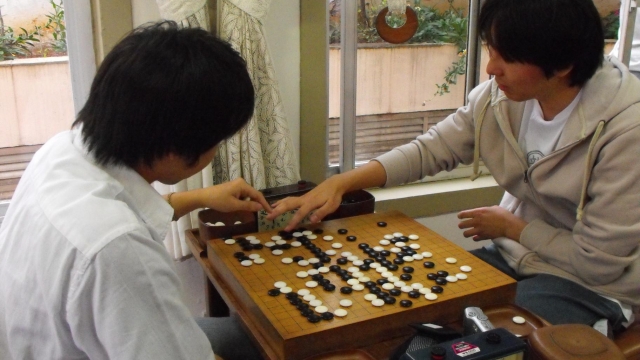 Two people play the board game go.