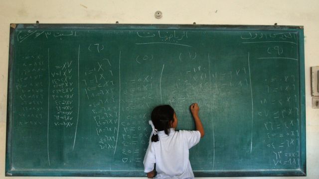 An Iraqi girl writes at a chalkboard
