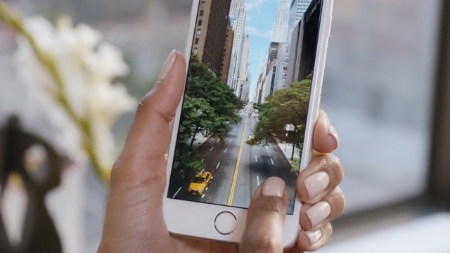 A finger taps on the screen of an iPhone 6S as it's being held.