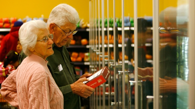 Shoppers browse the frozen foods section at a grocery store.