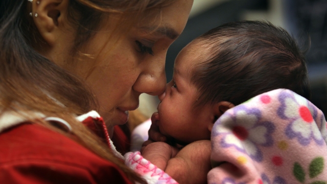 A woman holds her baby during a newborn checkup.