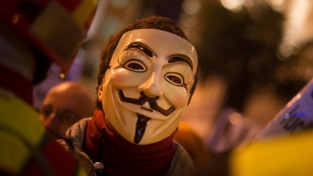 A protestor wears a mask of 'Anonymous' during a march by thousands of people in Madrid, Spain