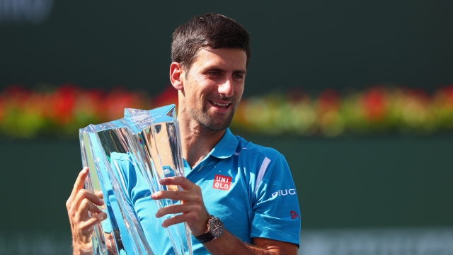 Novak Djokovic of Serbia holds up the winners trophy after his win over Milos Raonic.