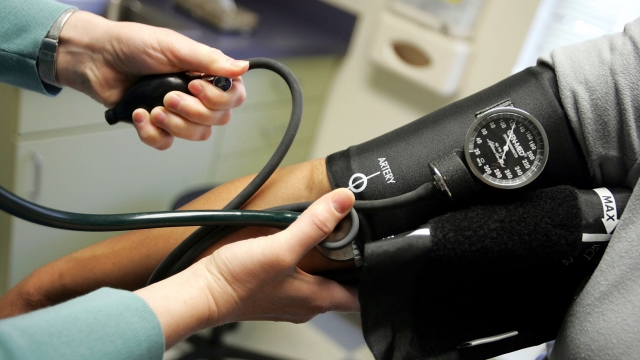 A doctor reads a blood pressure gauge during an examination of a patient.
