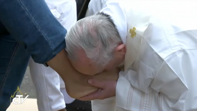 Pope Francis kisses the foot of a refugee in Castelnuovo di Porto.