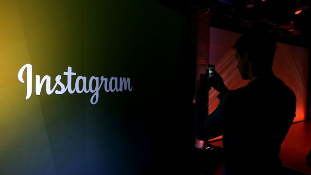 An attendee takes a photo of the Instagram logo during a press event at Facebook headquarters.
