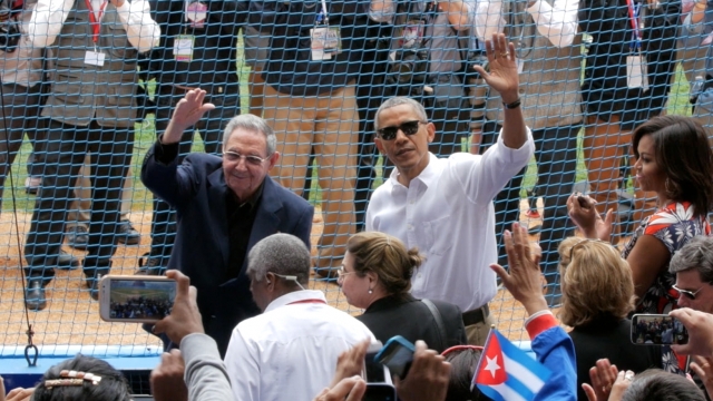 Presidents Raul Castro and Barack Obama greet the crowd at a baseball game in Cuba