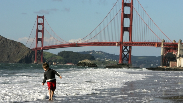 A boy plays at the beach near the Golden Gate bridge.