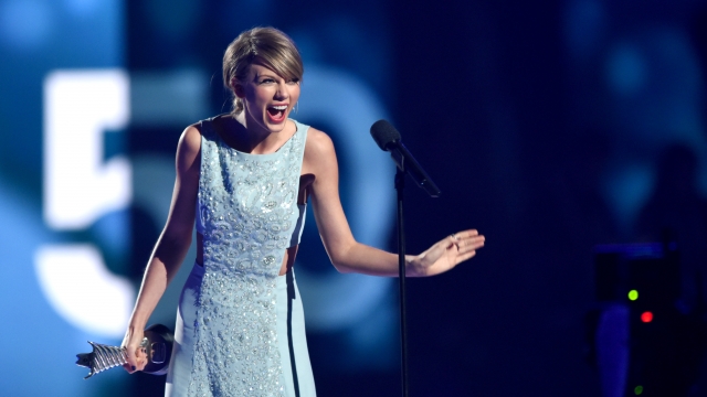 Taylor Swift laughs while accepting an award onstage.