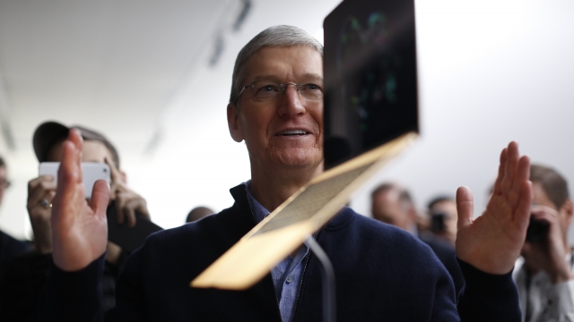 Apple CEO Tim Cook stands in front of an MacBook on display.