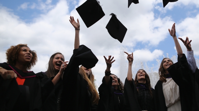 Students throw their caps in the air ahead of their graduation ceremony at the Royal Festival Hall on July 15, 2014