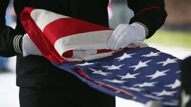 A U.S. Navy honor guard folds an American flag after removing it from a casket