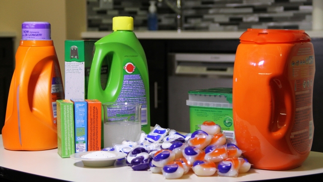 Laundry pods are shown in a pile beside liquid and powdered detergent.