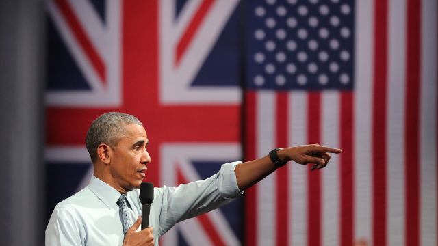 President Barack Obama at a town hall in the U.K. with a British and American flag behind him.