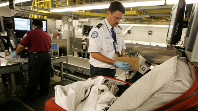 A TSA worker hand searches a bag at the Oakland International Airport.