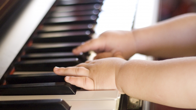 An image of a child playing piano keys.