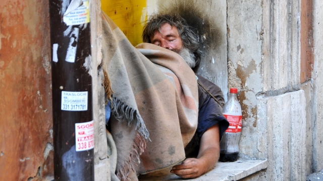 A homeless man sleeps near a building in Rome.
