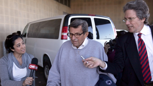 Joe Paterno is surrounded by the media while leaving the team's football building