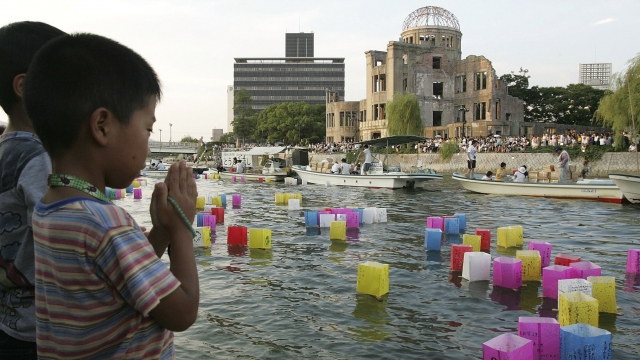 A young boy prays after releasing a floating lantern onto the Motoyasu river in front of the Atomic Bomb Dome.