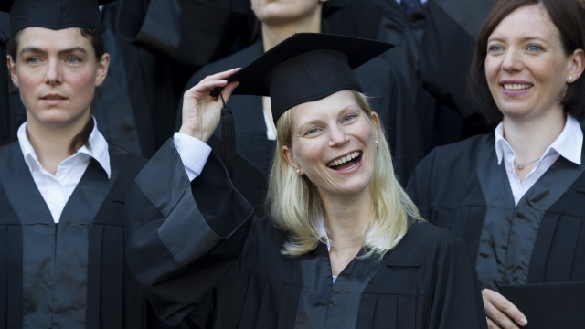 Graduates in gown and caps celebrate their graduation at the HHL Leipzig Graduate School of Management in Germany.