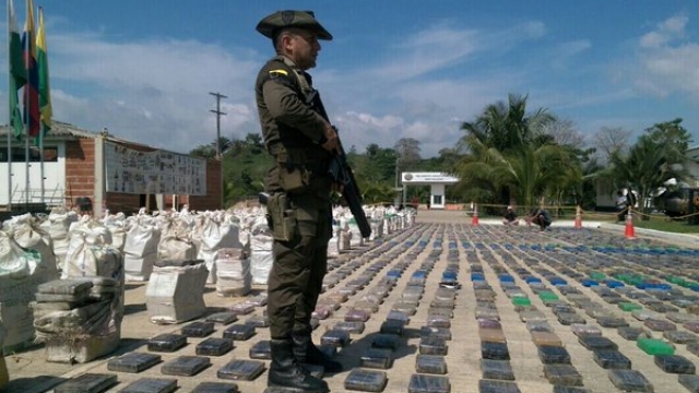 A Colombian police officer stands over packages of confiscated cocaine.