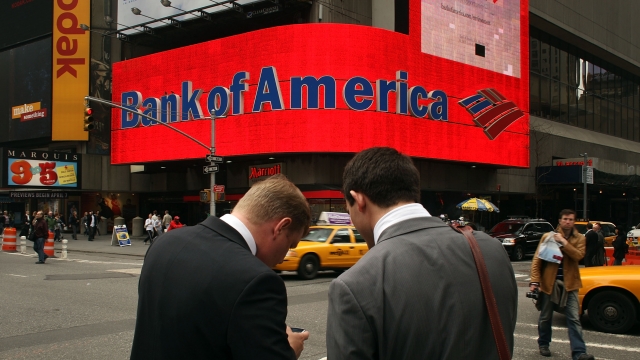 Two men stand in front of a Bank of America billboard in Times Square.