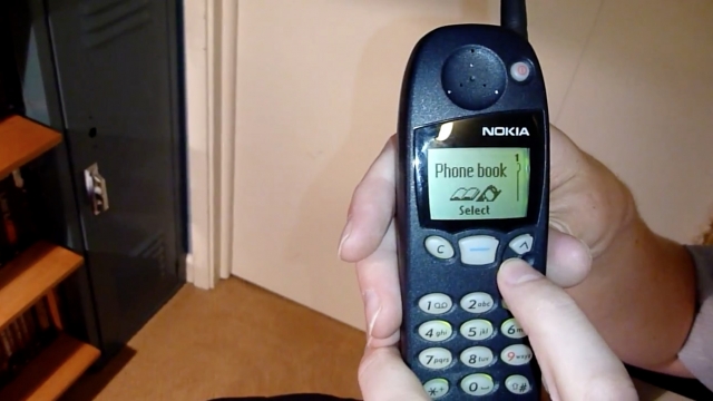 Man holds up an old Nokia 5190 brick phone.