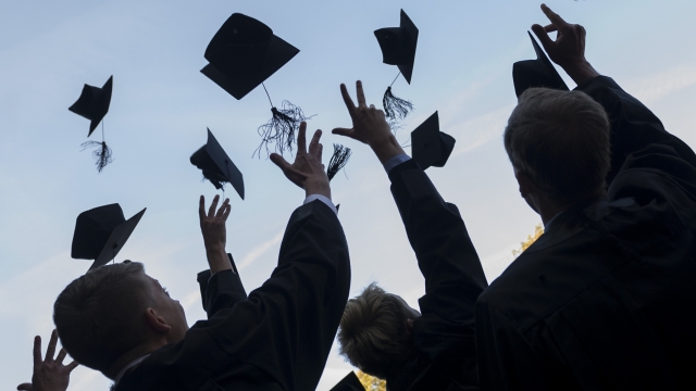 Graduates in gown and caps celebrate their graduation.