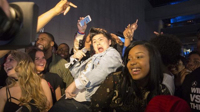 A man performs at Trap Karaoke at Barclays Center while others dance and cheer him on.