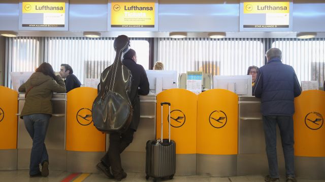 People stand in line at a Lufthansa ticket counter.