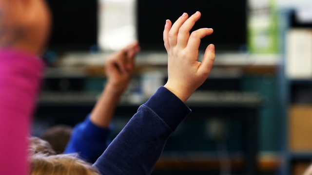 A student raises his hand in a school classroom.
