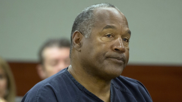 O.J. Simpson sits in a courtroom in a navy-colored prison uniform.