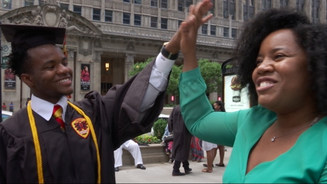 A mother high-fives her son, a college-bound graduate of Urban Prep Academies.