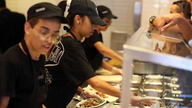 Chipotle restaurant workers fill orders on the day that the company announced it will only use non-GMO ingredients.