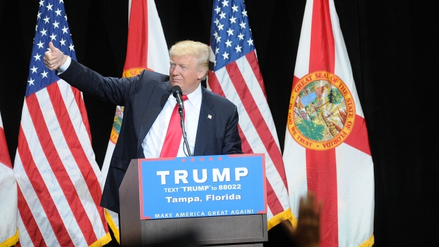 Republican presidential candidate Donald Trump stands behind a lectern in front of flags