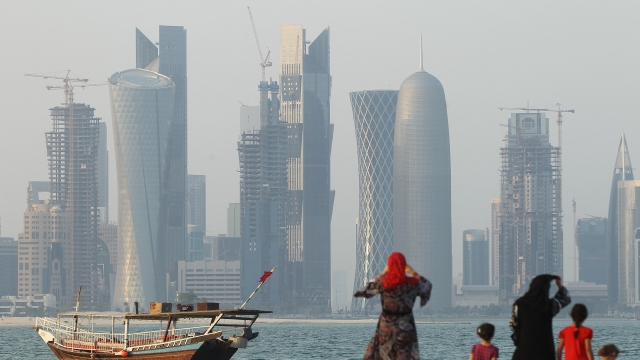 Doha, Qatar, in focus in the background with a fuzzy image of a boat and people in the foreground