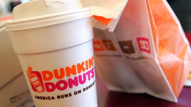 A cup of Dunkin' Donuts coffee and a doughnut bag sit on a counter