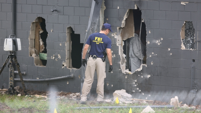 FBI agents investigate near the damaged rear wall of the Pulse nightclub where a massacre took place Sunday.